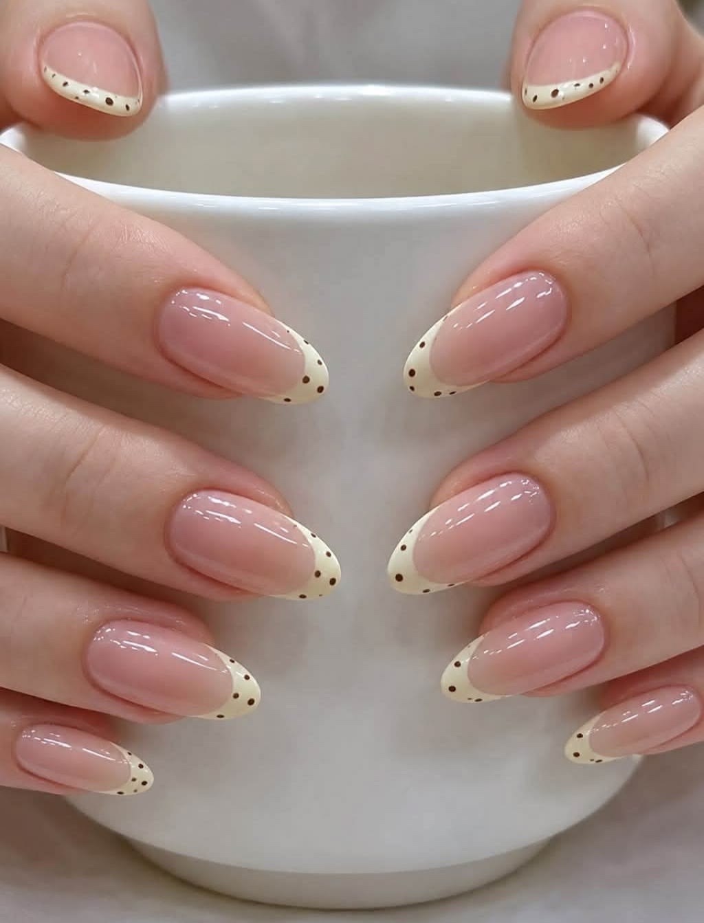 Referencia de uñas almendradas con punta francesa crema y puntos café